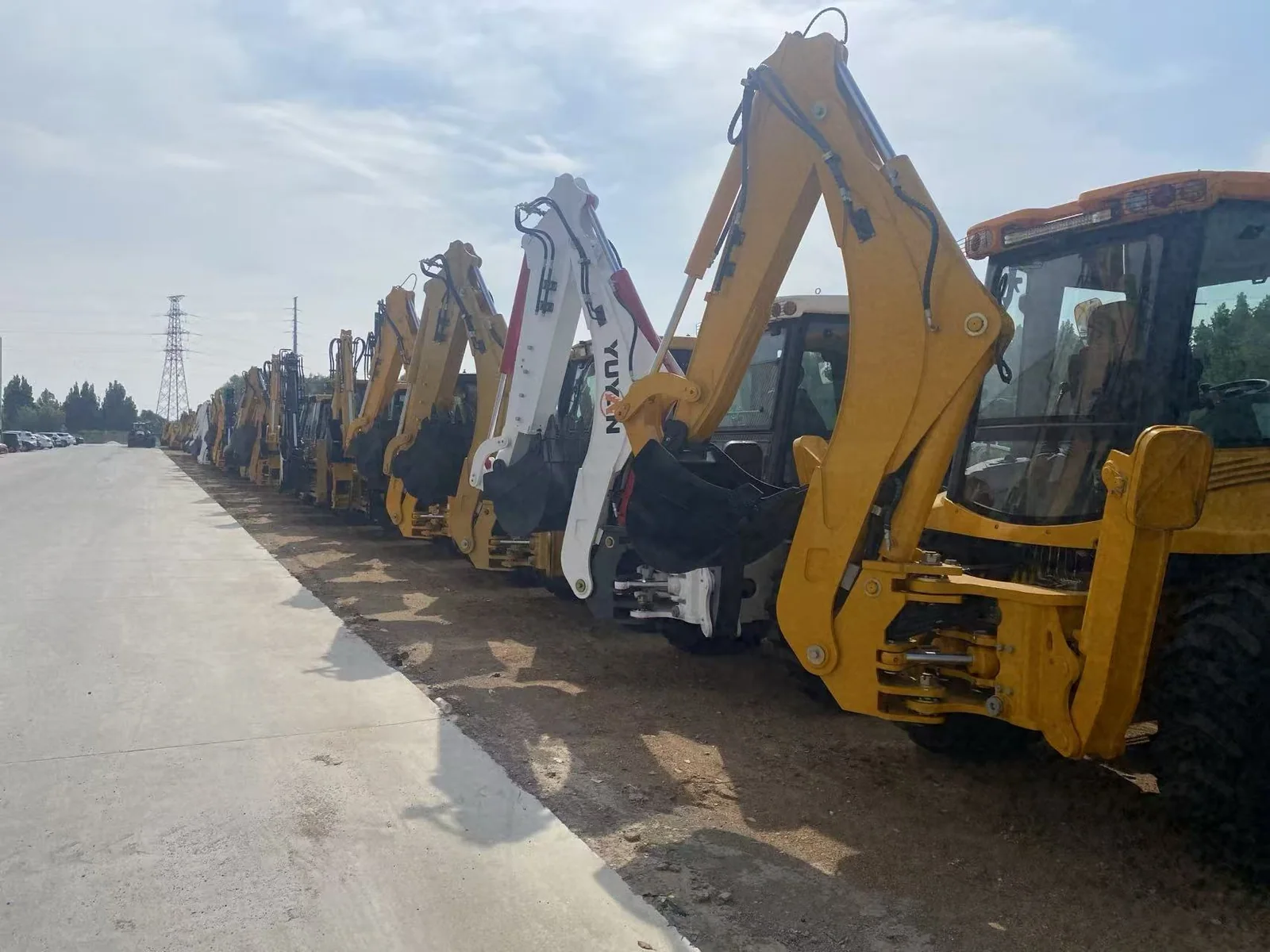 Row of backhoe loaders photographed in equipment yard
