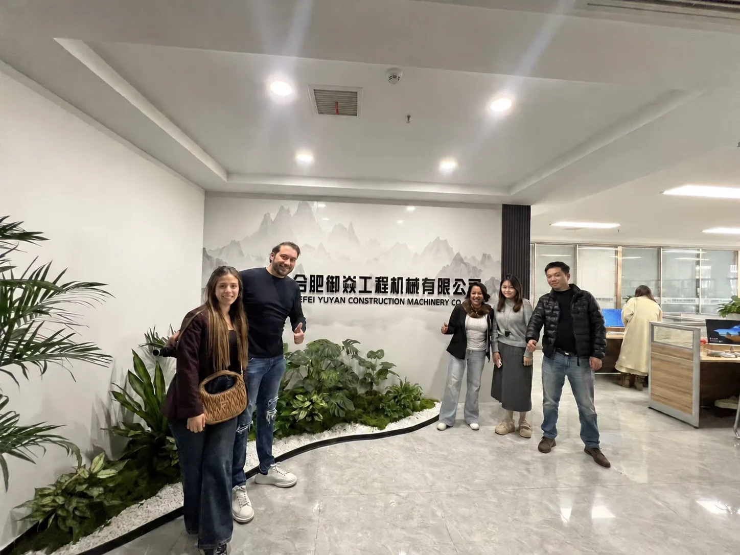 Visitors posing in front of the Hefei Yuyan Construction Machinery Co., Ltd. office sign