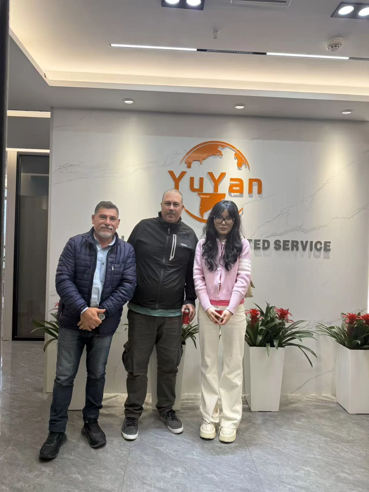 Visitors pose in front of the YUYAN-brand logo for a group photo