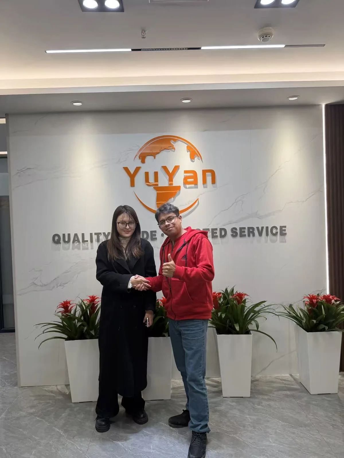 Two people shaking hands in front of the YUYAN-brand wall in the office