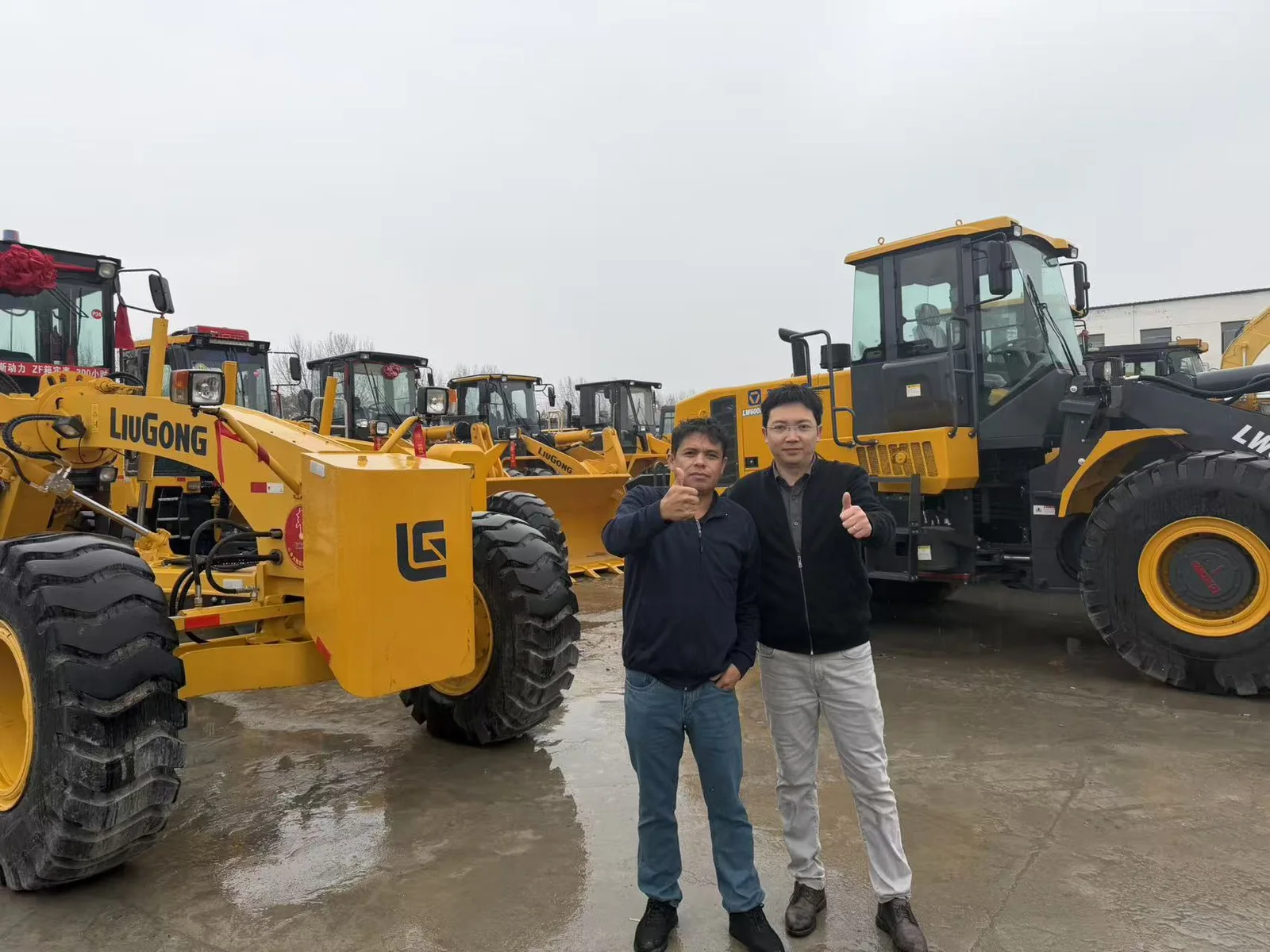 Two people standing between wheel loaders and LiuGong equipment in an equipment yard