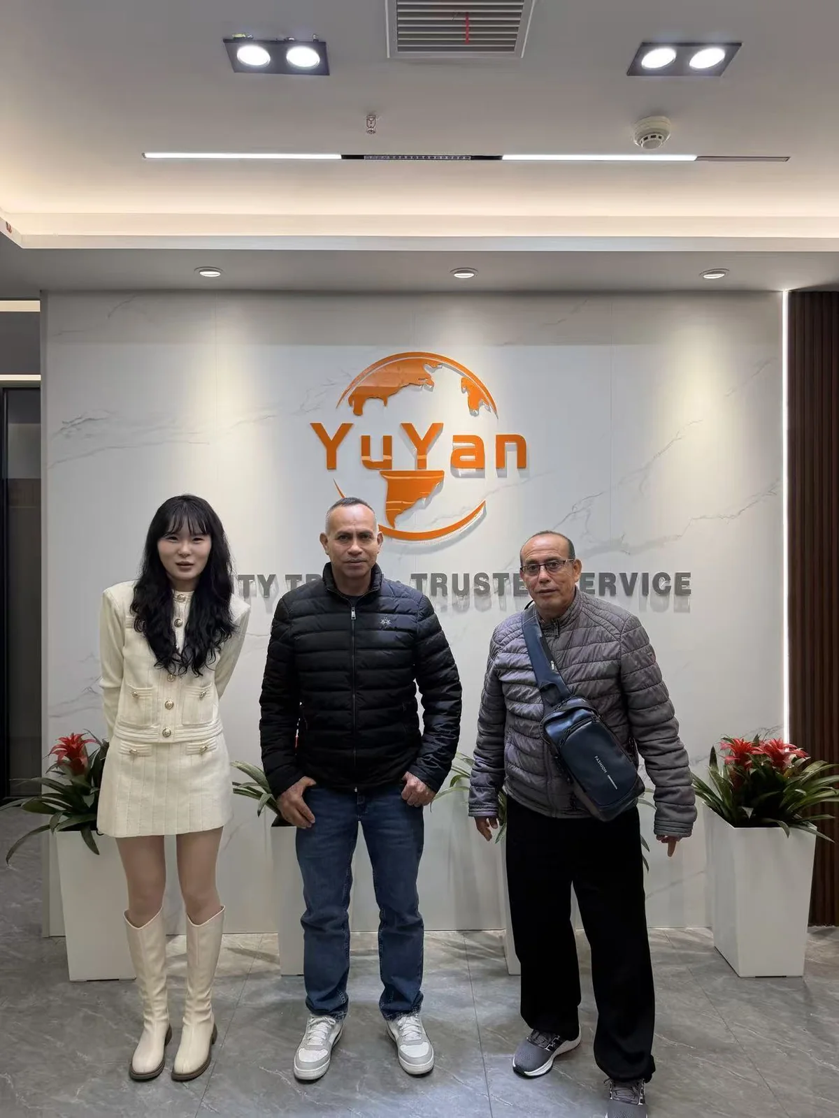 Three people gathered in front of the YUYAN-brand sign