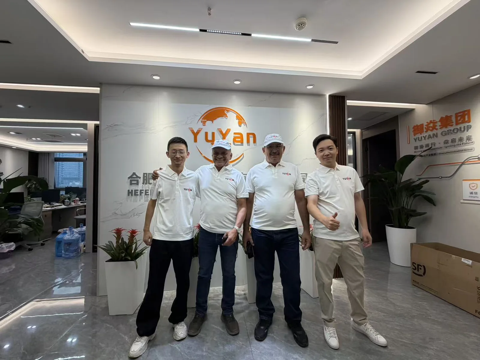 Four people posing in front of the YUYAN sign in the office