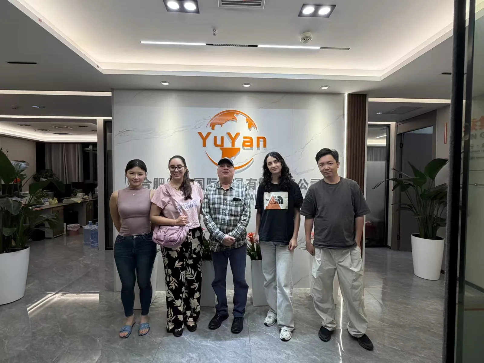 Five people posing in front of the YUYAN sign in the office